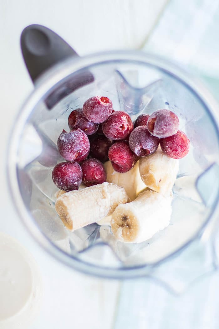 A photos showing the simple process of adding frozen fruit and coconut milk to a blender.