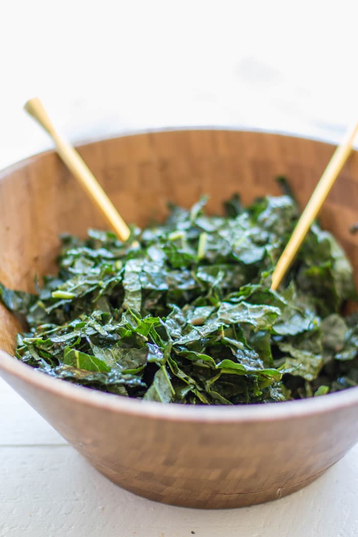 A bowl showing how to massage dressing into the kale to soften it.