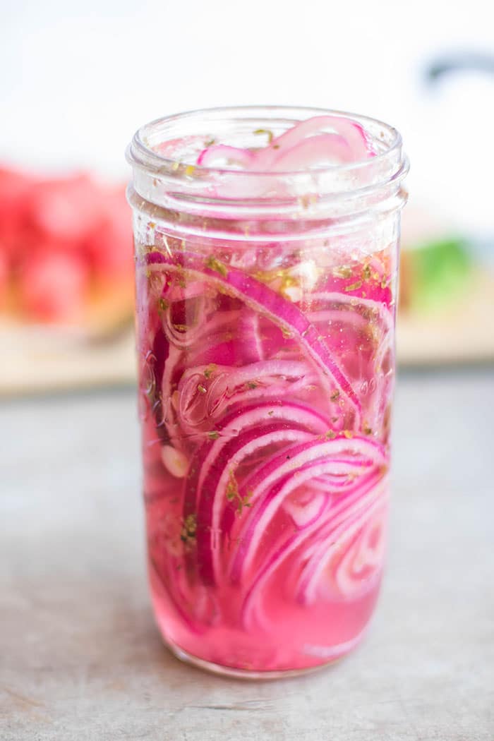 A jar showing beautiful red marinated onions.