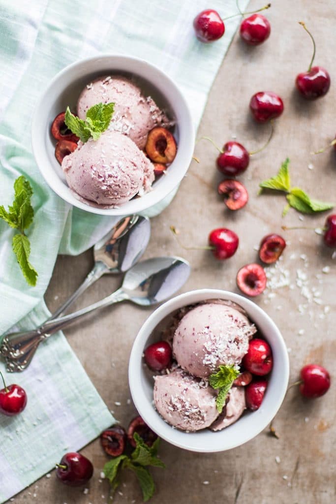 Two bowls both filled with 2 scoops of vegan cherry ice cream.