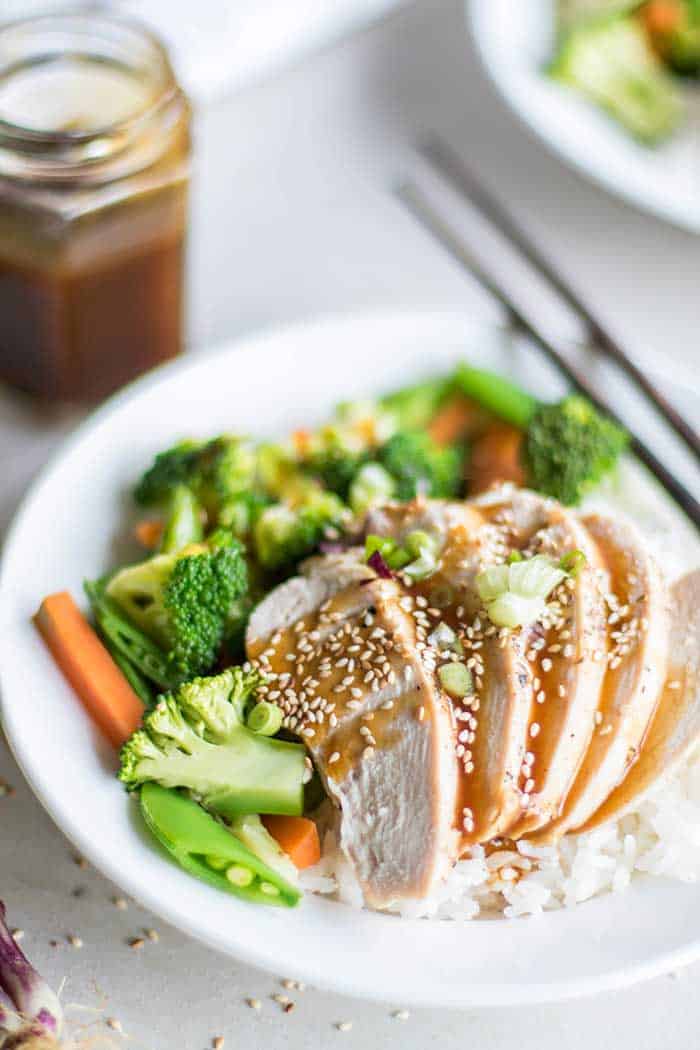 A plate with rice, vegetables, and chicken, drizzled with a soy free teriyaki sauce.