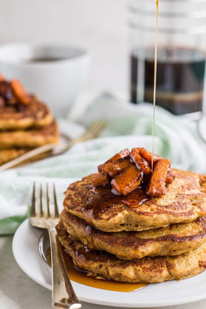 Gluten free pancakes with caramelized butternut squash, being drizzled with syrup.