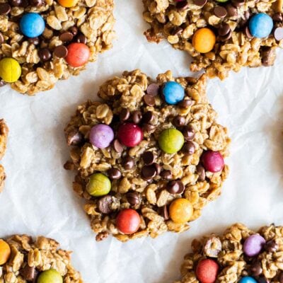 A close up of colorful gluten free monster cookies studded with chocolate and candy coated chocolate drops.