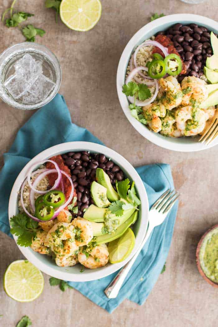 Two bowls filled with cauliflower rice, shrimp, black beans and avocado.