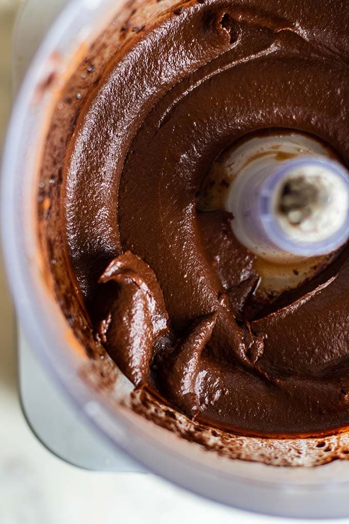 A thick fudgy chocolate frosting in a food processor bowl.