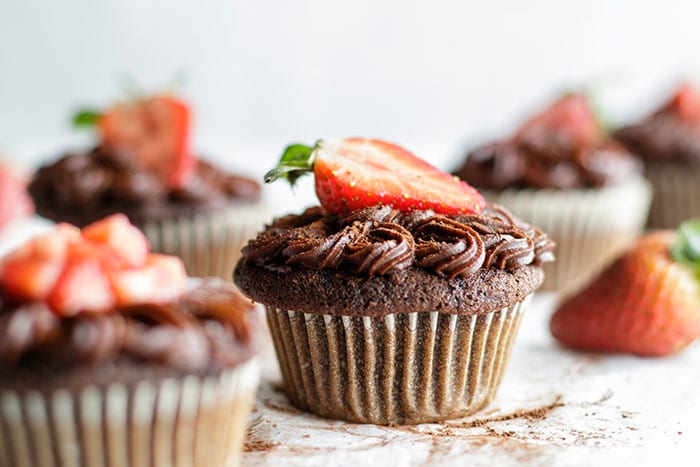 A paleo chocolate cupcake with a strawberry on top.