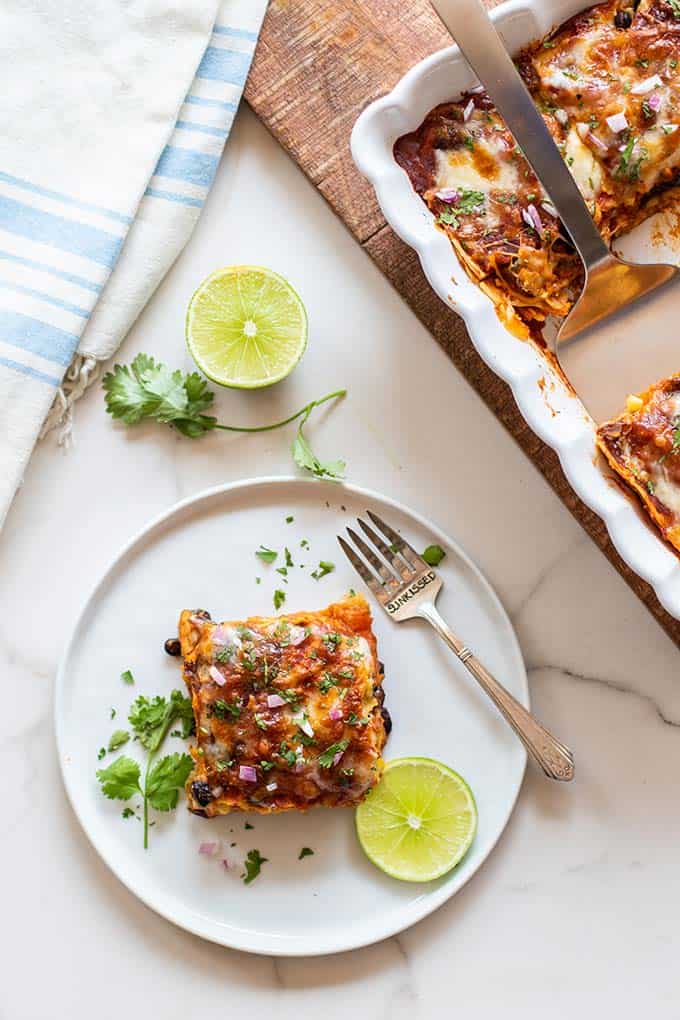 A slice of vegetarian enchilada casserole garnished with cilantro and lime.