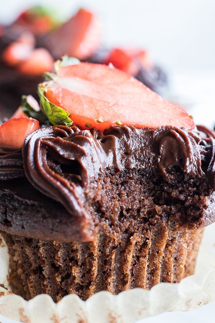 A closeup of a paleo chocolate cupcake with a bite taken out of it.