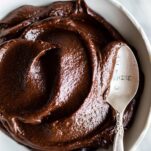 A bowl filled with a thick, fudgy chocolate frosting.