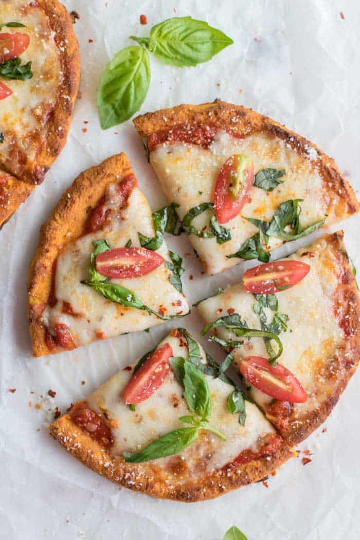 A mini pizza made on a sweet potato pizza crust cut into 4 slices