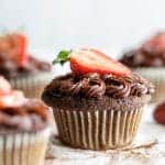 A paleo chocolate cupcake with a strawberry on top.