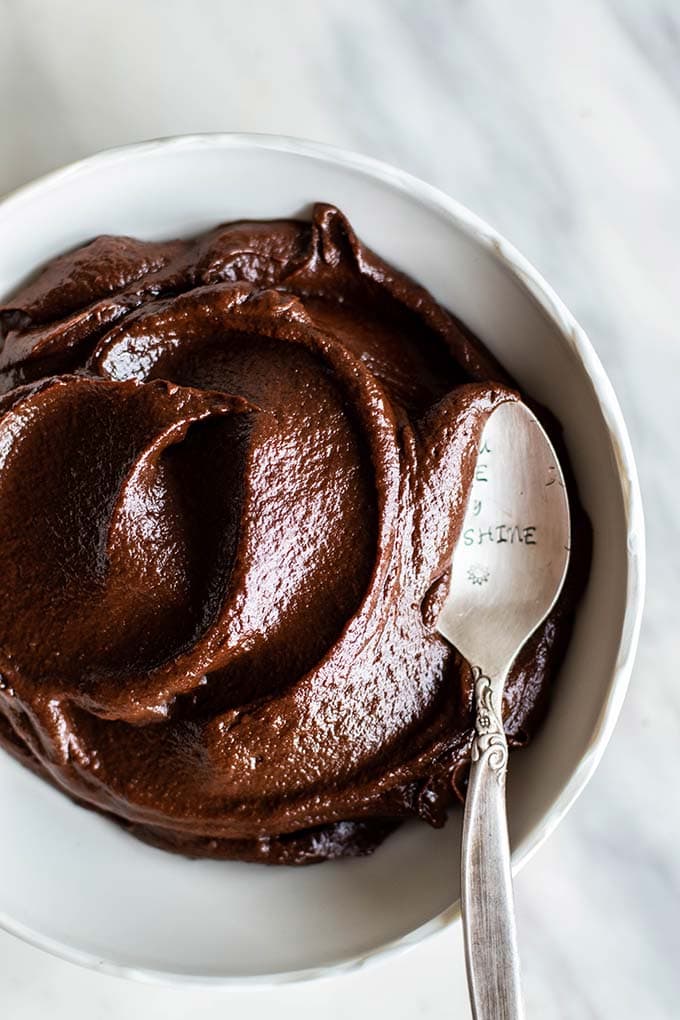 A bowl filled with a thick, fudgy chocolate frosting.