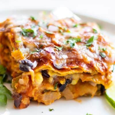 A slice of vegetarian enchilada casserole garnished with cilantro and lime.