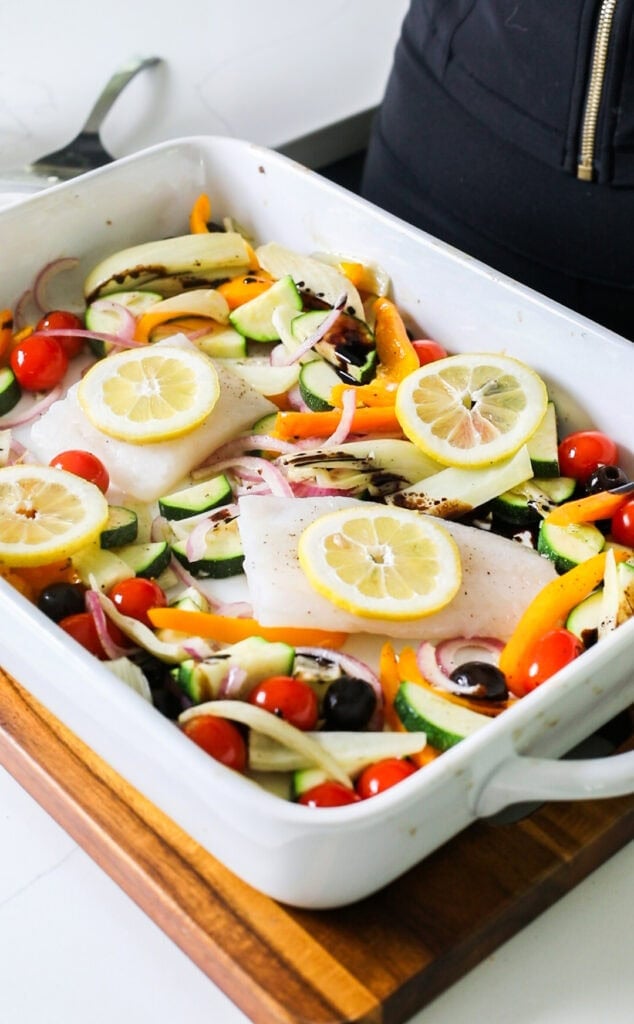The baking dish with fish and lemon slices added.