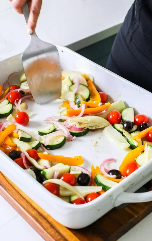 The baking dish with vegetables, showing making space for the fish.