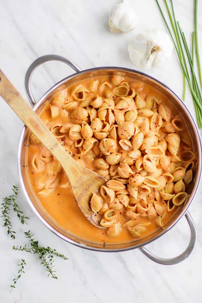 A pot with gluten free shells pasta covered in a creamy tomato pasta sauce.