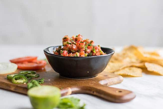 A black bowl of salsa with chips.