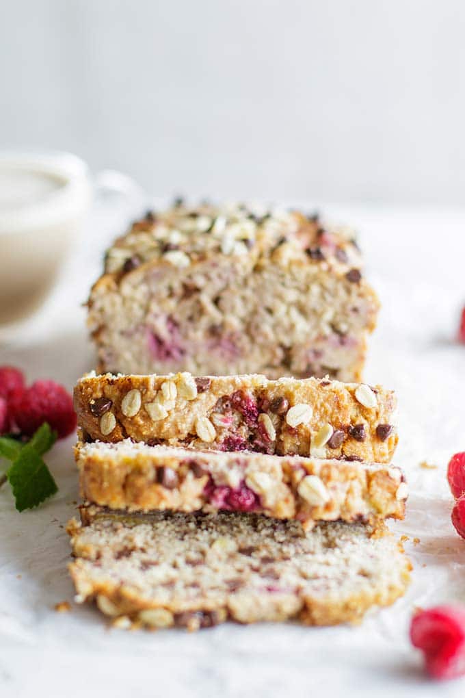 A loaf of banana raspberry bread cut into thick slices and stuffed with dark chocolate chips.