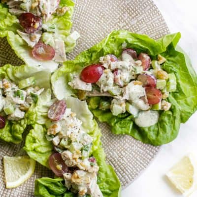 A plate with 4 leaves of lettuce filled with a paleo chicken salad.