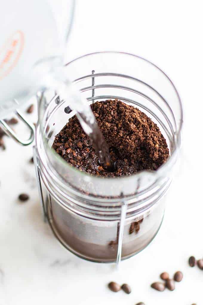 Water being poured over coffee grounds in a French press.