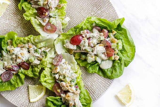 A plate with 4 leaves of lettuce filled with a paleo chicken salad.