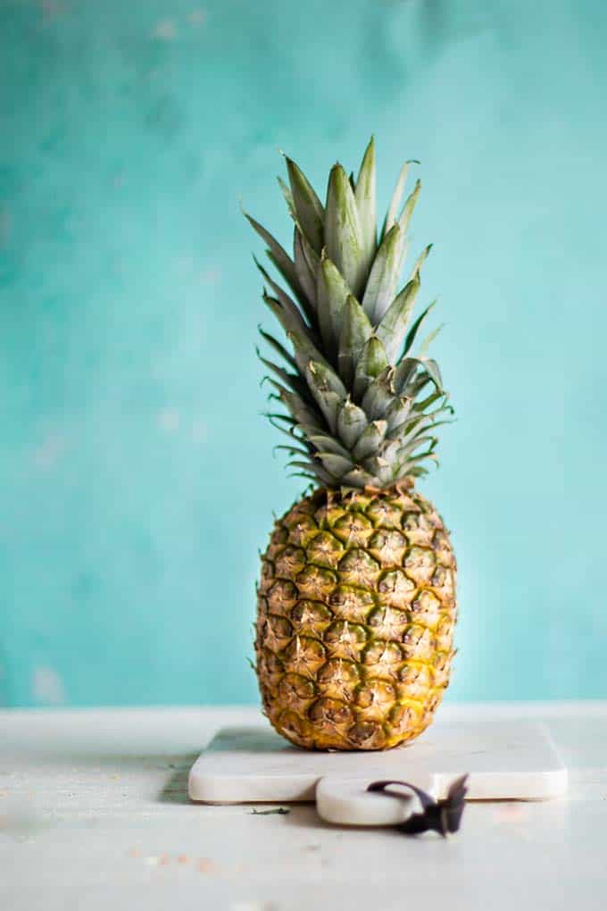 A whole pineapple sitting on a cutting board.