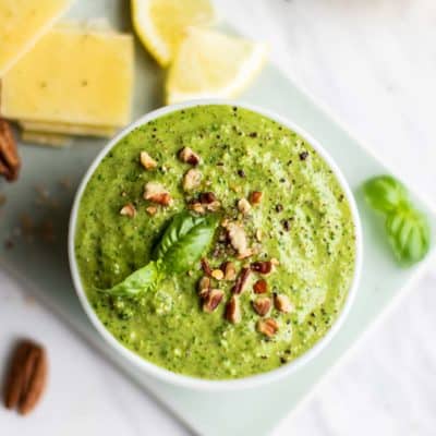 A close up of a blue bowl filled with arugula pesto.