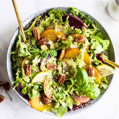 A large bowl of cold beet salad with pecans and lemon next to it.