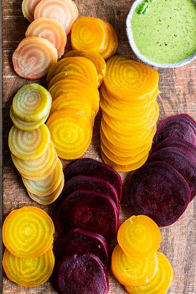 A cutting board covered in sliced golden and red beets.