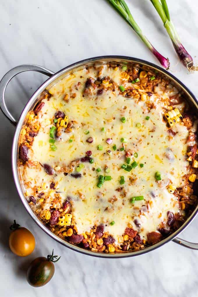 A pan of cooked mexican quinoa topped with melted cheese.