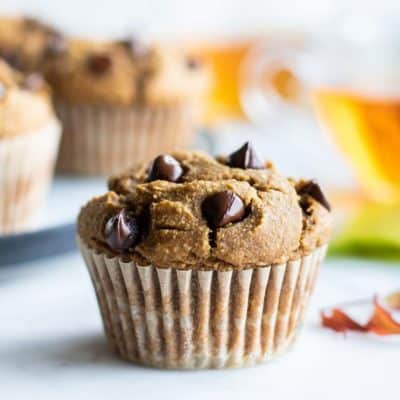 Healthy Pumpkin Chocolate Chip Muffins sitting on a table with 2 cups of tea.