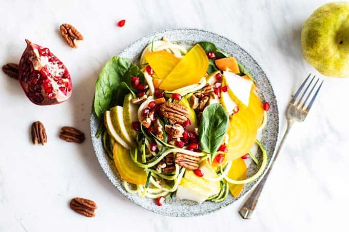 A beautiful zoodle salad topped with pears, pomegranate, and golden beets.
