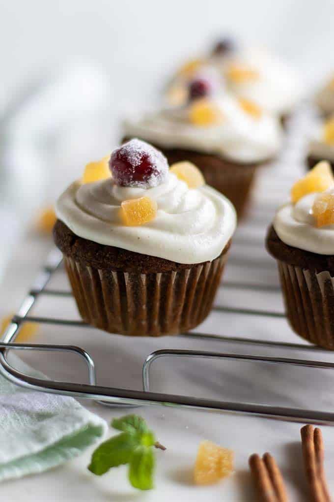 Gluten free gingerbread cupcakes topped with a cream cheese icing on a rack.