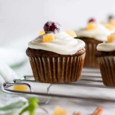 A gluten free gingerbread cupcake iced with cream cheese frosting and topped with a sugared cranberry.