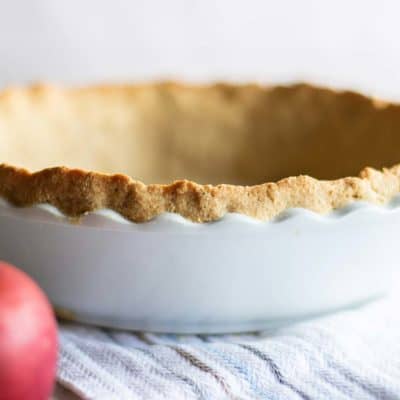 An almond flour pie crust baked and shown with apples.
