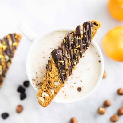 A slice of gluten free biscotti resting on top of a coffee mug.