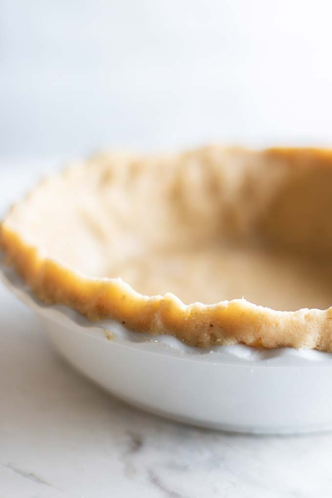 A gluten free pie crust pressed into a white pie plate.