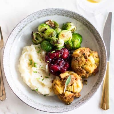 A plate with two apple sausage stuffing bals on a holiday food plate.