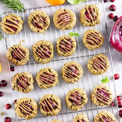 Baked cranberry breakfast cookies drizzled with sunflower seed butter cooling on a rack.
