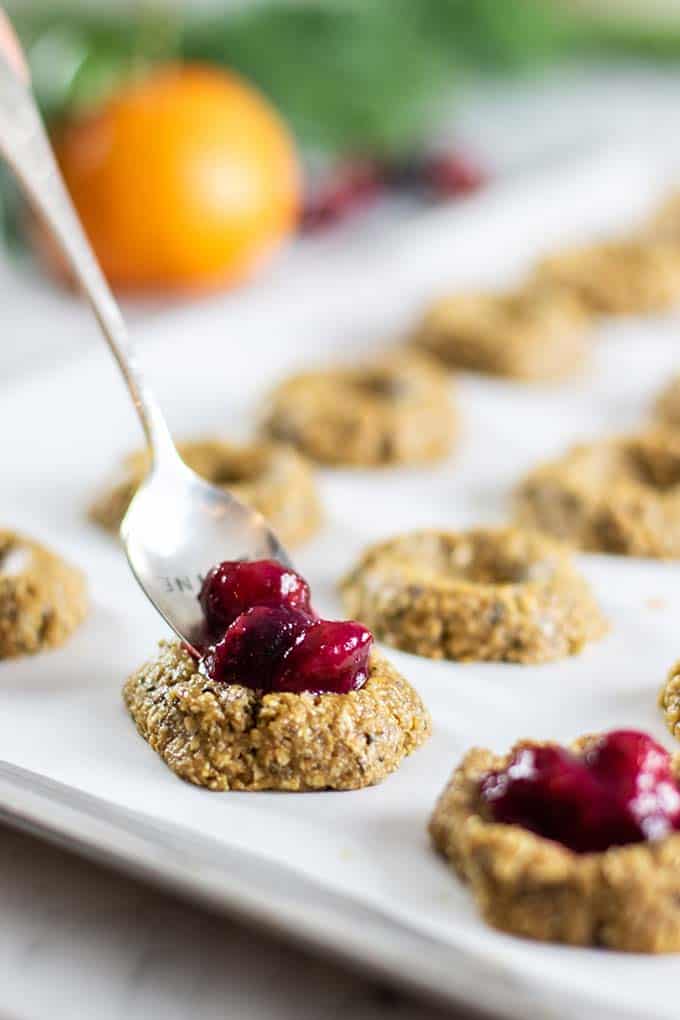 A tray of breakfast cookies being filled with cranberry jam.