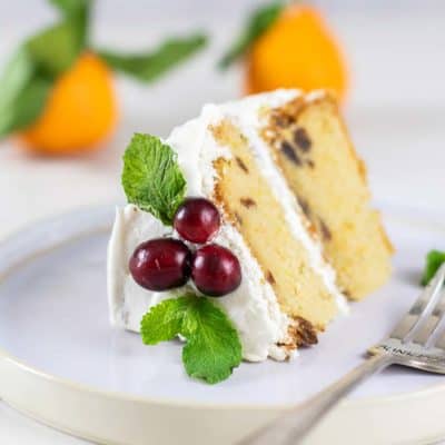 A slice of almond flour cake decorated with cranberries and mint.