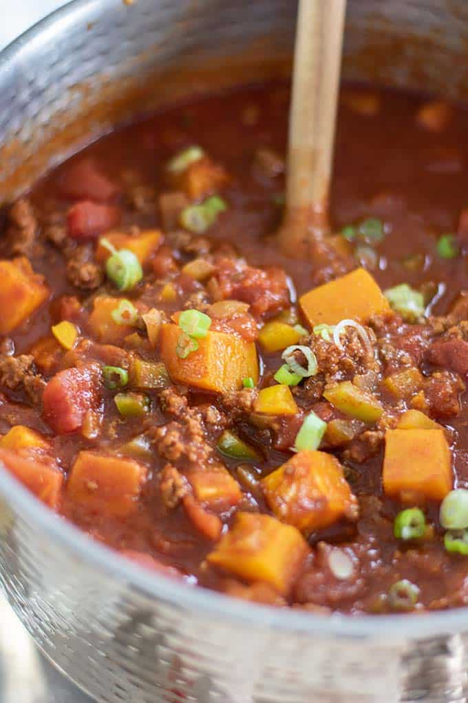 A pot of chili with beef, butternut squash, and peppers.