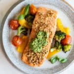 Pesto salmon served with tomatoes, peppers and broccoli.