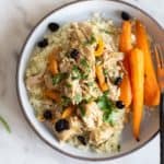 A plate with a serving of crockpot moroccan chicken, carrots, and cauliflower rice.