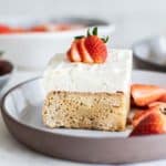 A slice of almond flour gluten free tres leches cake with strawberry slices.