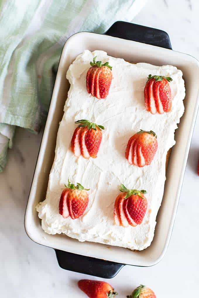 A top view of a whole tres leches cake topped with strawberries.