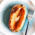 A soft baked sweet potato topped with butter and pepper.