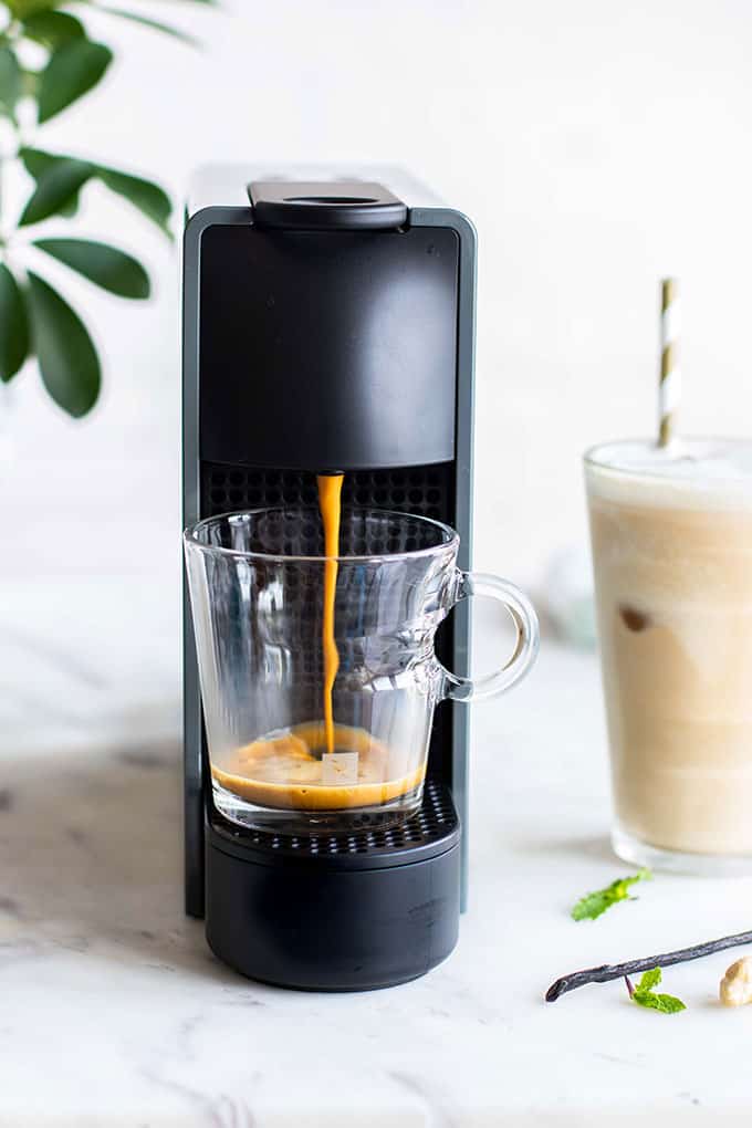 A Nespresso machine with coffee being made.