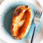 A soft baked sweet potato topped with butter and pepper.