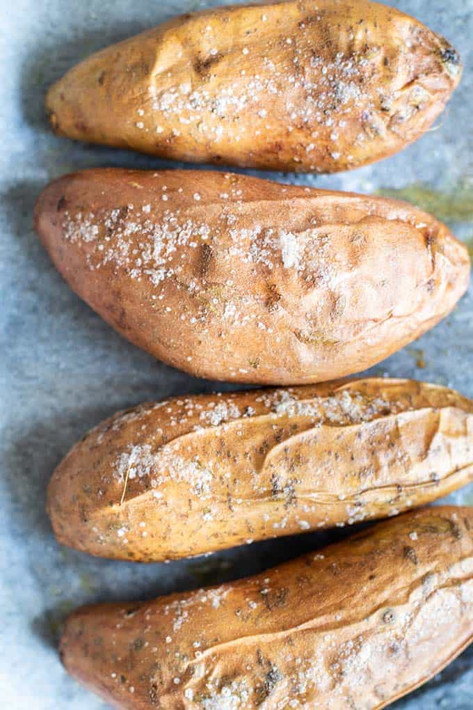 4 baked sweet potatoes on a baking tray.